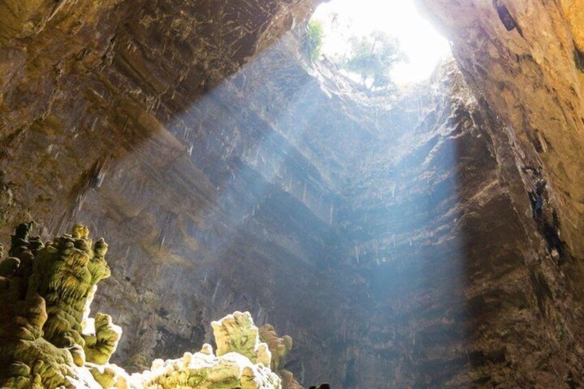 A cave with stalactites and a beam of light entering from above. 2