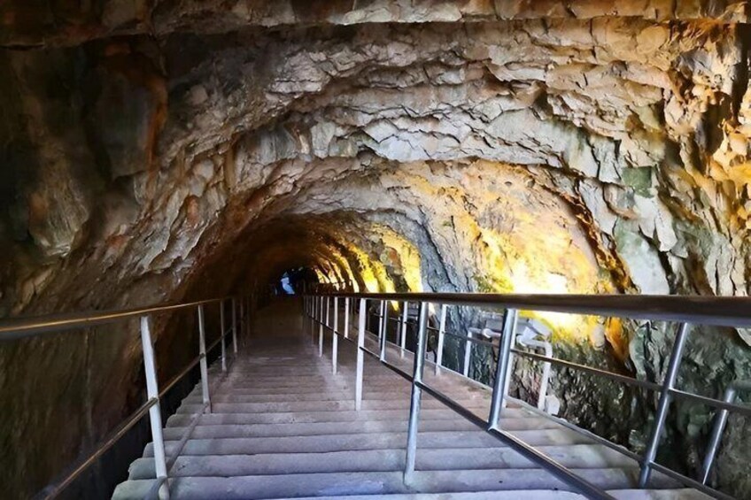A stone staircase in a cave with metal railings. 3