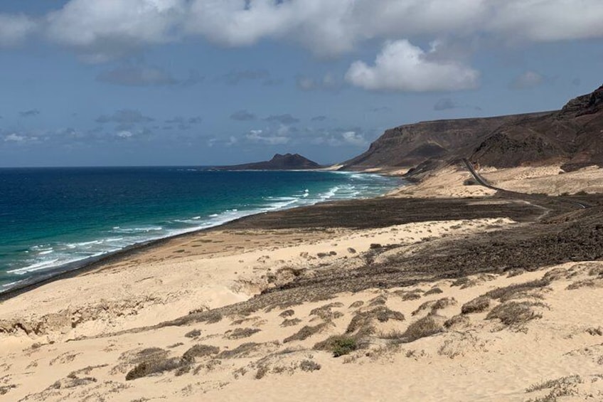 A coastal landscape with a sandy beach, ocean, and rocky cliffs. 3