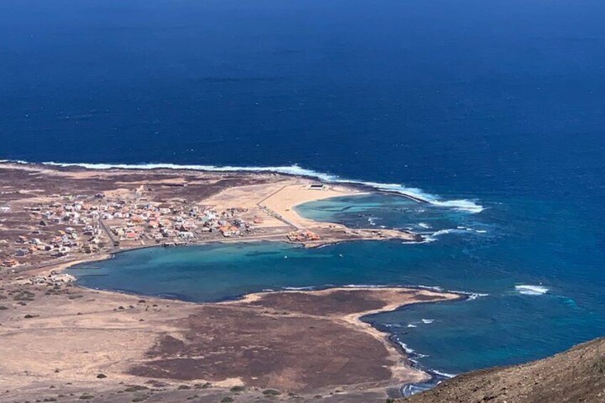 A coastal landscape with a beach, a small town, and a bay. 1