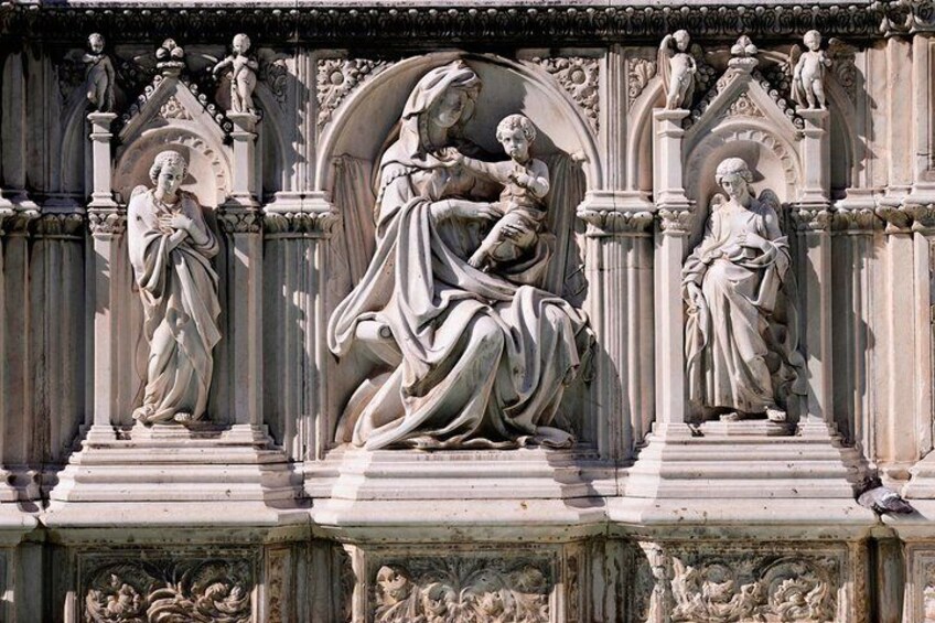 A detailed stone carving of a religious scene with figures in dynamic poses, set within an ornate architectural structure. 2