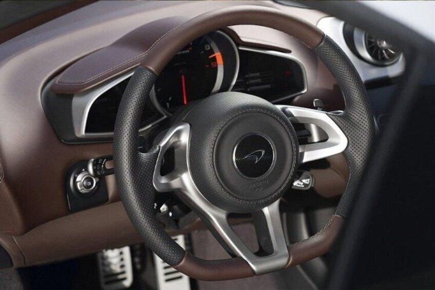 A car's steering wheel with a logo, a speedometer, and a gear shift. 4