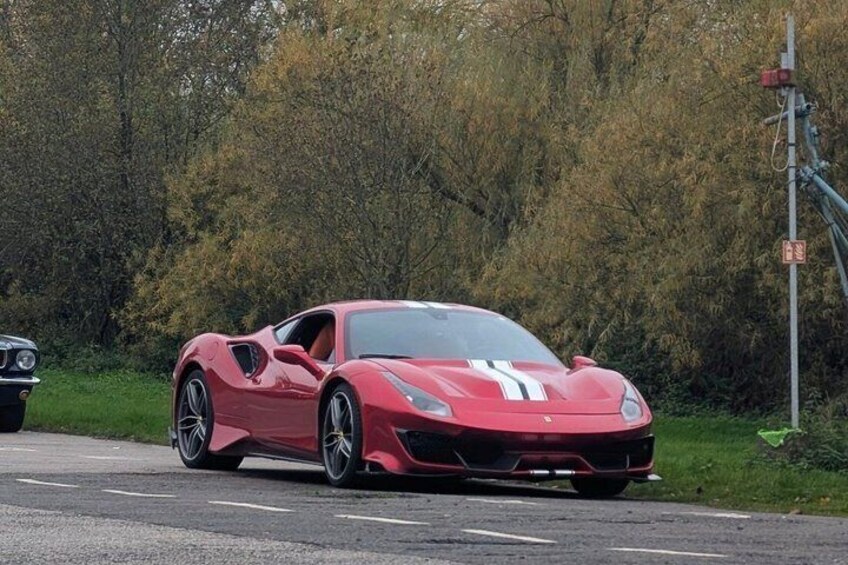 A red sports car parked on a road with trees in the background. 3