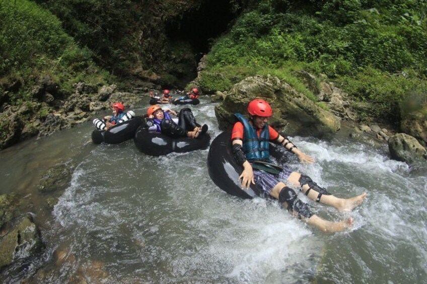 People rafting down a river surrounded by greenery. 2