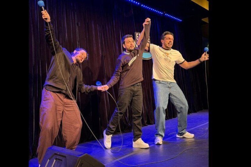 Three people on a stage with microphones, holding a rope. 2