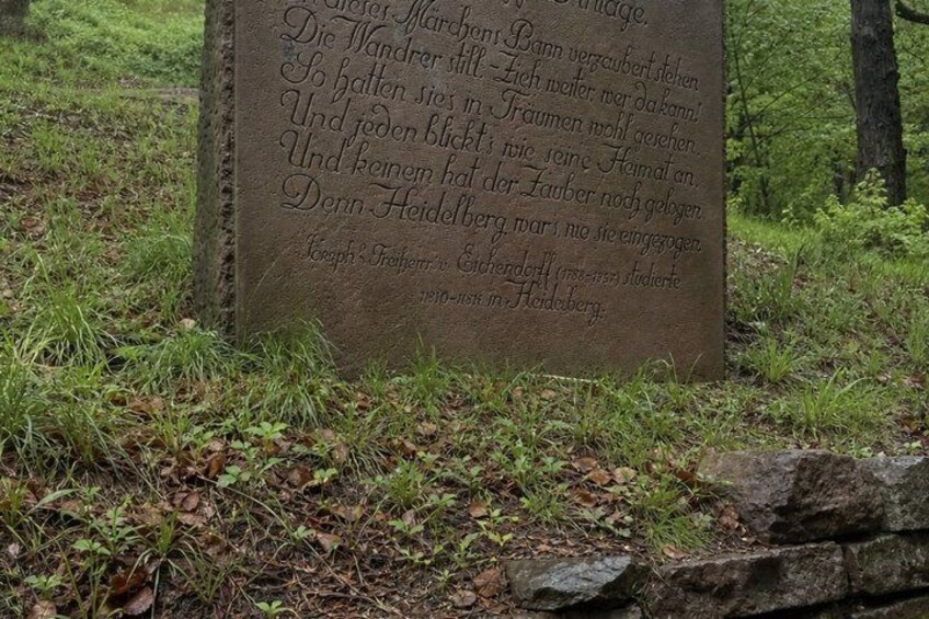 A stone monument with engraved text in a natural setting. 5