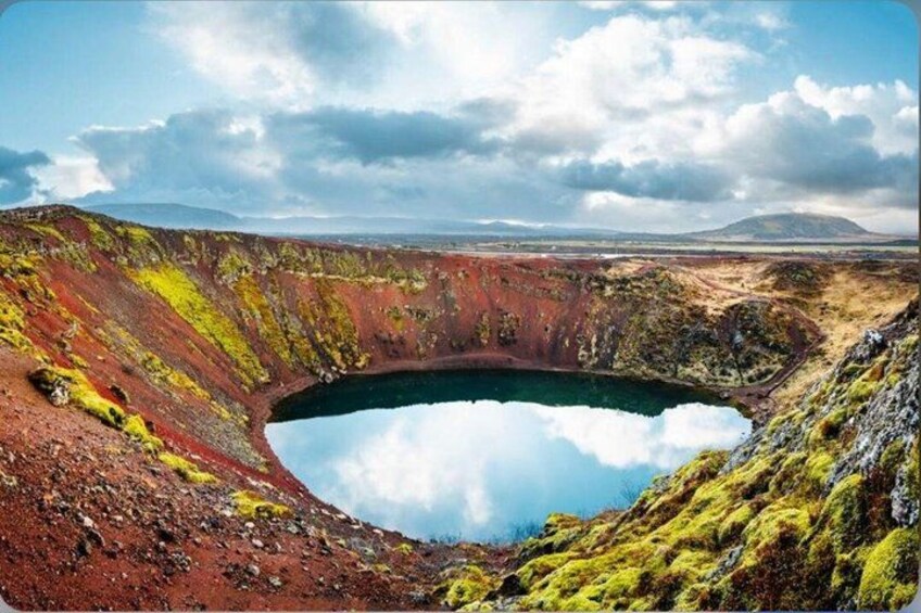 A large crater with a reflective water surface surrounded by colorful volcanic terrain. 4
