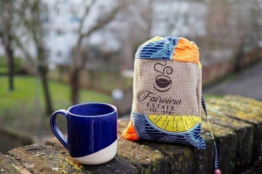 A blue mug and a burlap sack with a logo and text on a stone ledge. 5