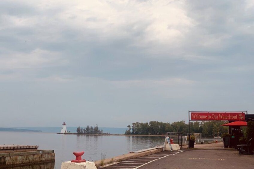 A waterfront with a lighthouse, a sign reading 'Welcome to Our Waterfront,' and a cloudy sky. 3
