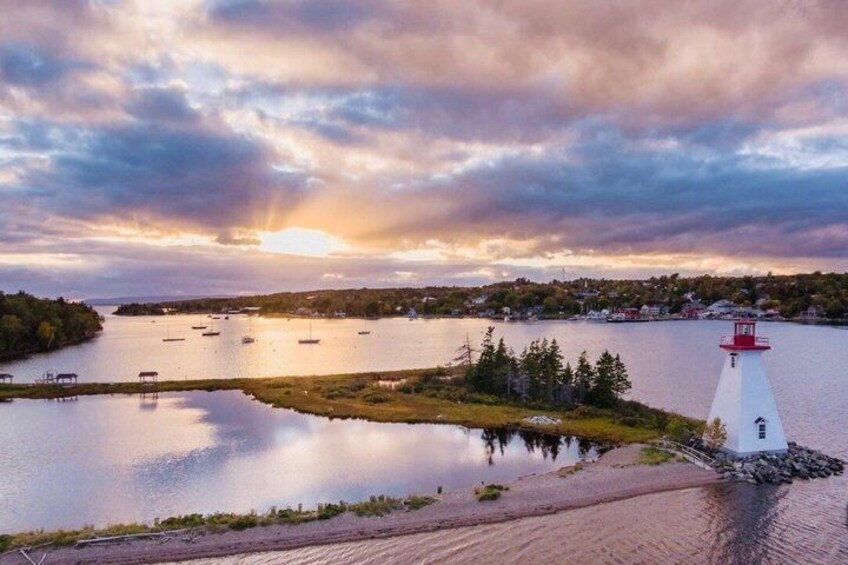 A lighthouse on a small island, calm water, and a sunset. 4