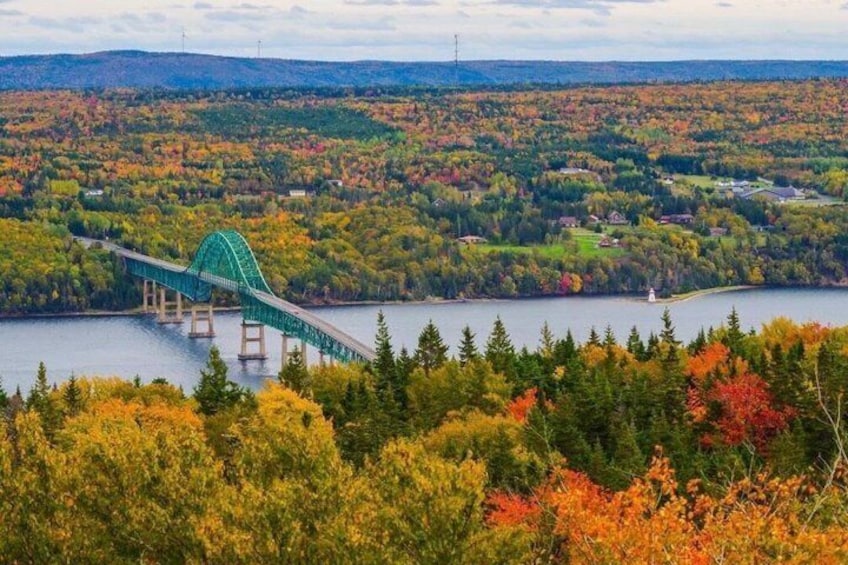A green bridge over a lake surrounded by autumn-colored trees. 1