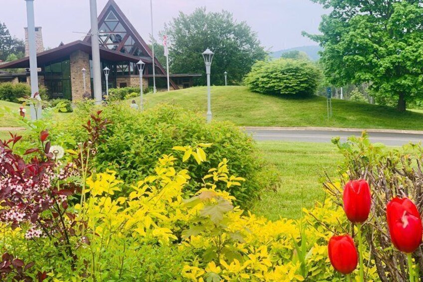 A landscaped garden with yellow flowers, red tulips, and a building with a triangular roof. 2