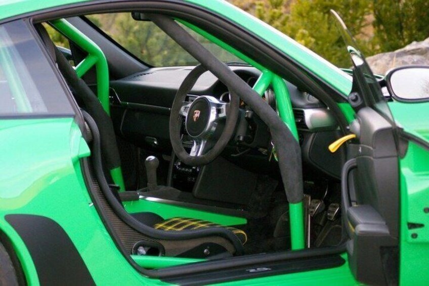 A green sports car interior with a steering wheel, dashboard, and gear shift. 4