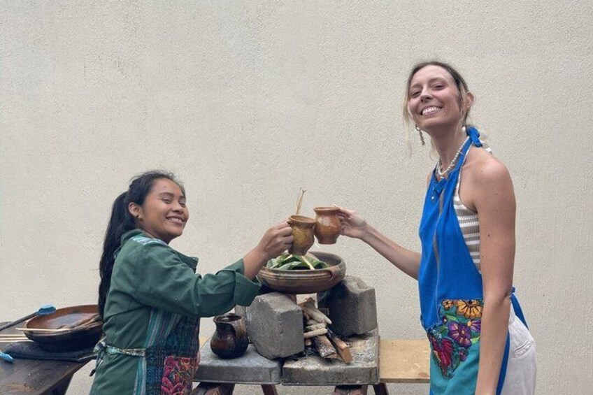 Two people sharing a meal with traditional pottery and a stone grinding surface. 2