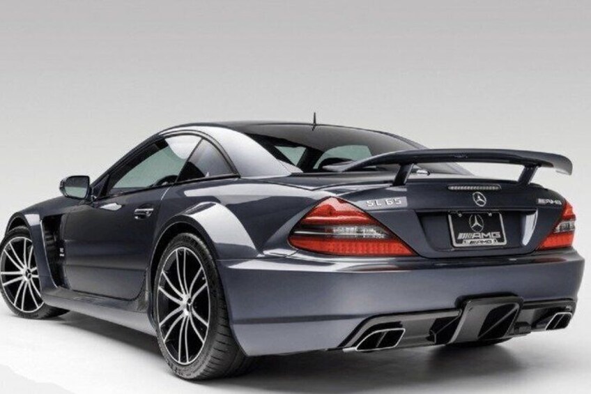 A dark-colored luxury car with a rear spoiler, dual exhaust pipes, and a license plate. 5