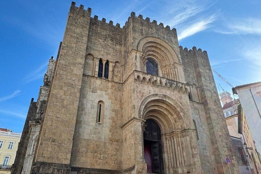 A historic stone building with a large arched entrance and a tower with battlements. 3