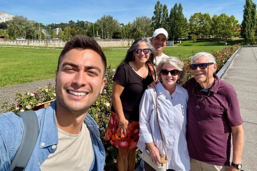 A group of people standing on a paved path with a grassy field and trees in the background. 4