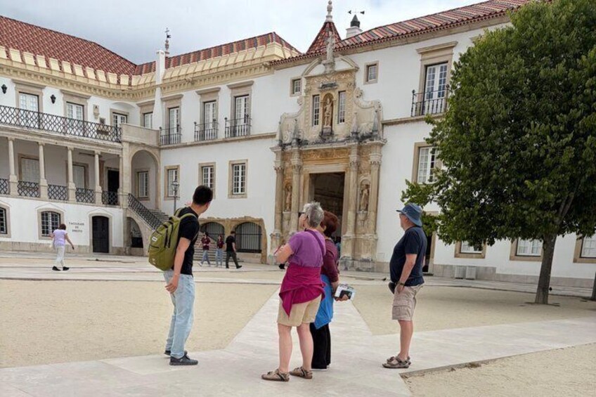 A historic building with a courtyard, tourists, and a tree. 1
