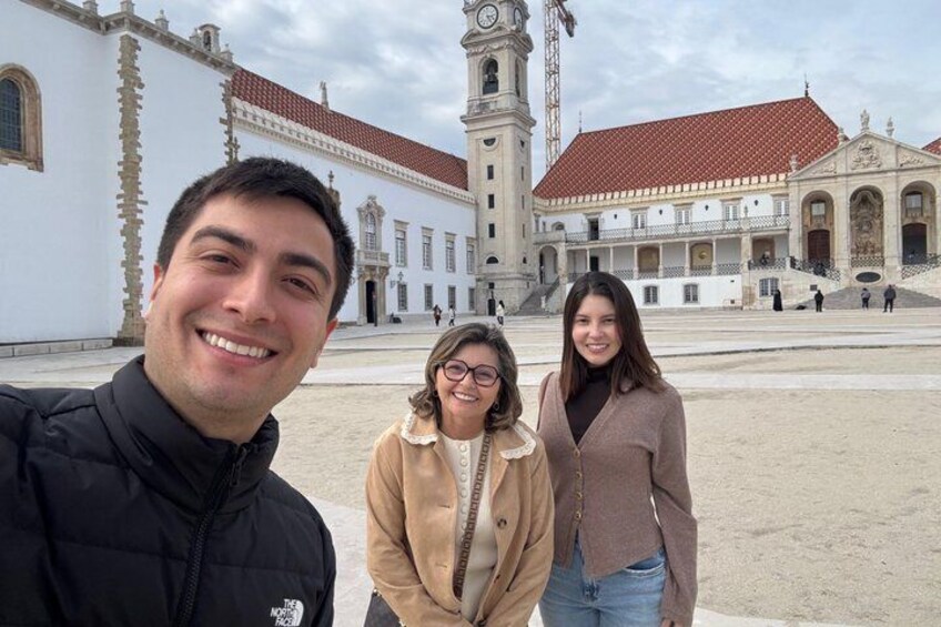 A historical building with a clock tower, a large open plaza, and a person taking a selfie. 5