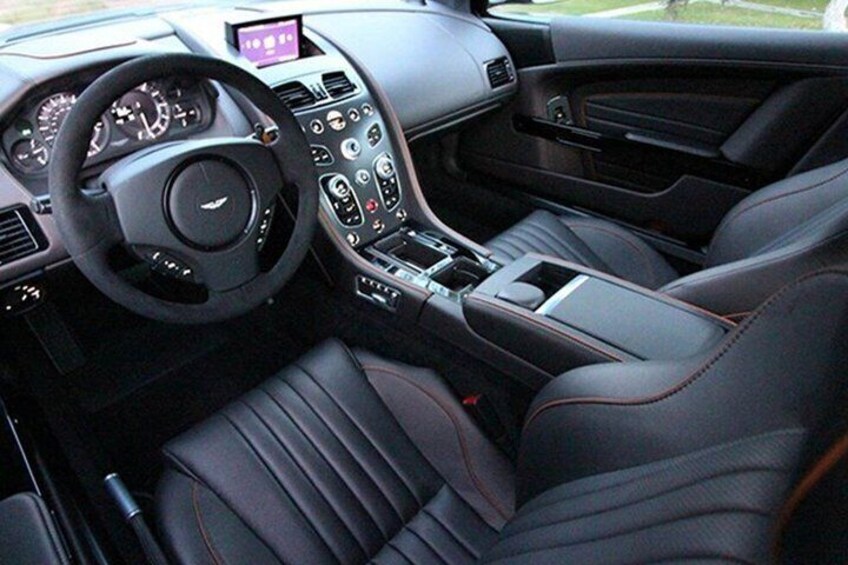 A car's interior with leather seats, a steering wheel, and a dashboard with various controls. 5