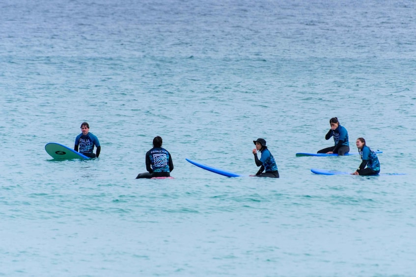 A group of surfers sitting on surfboards in the ocean. 5
