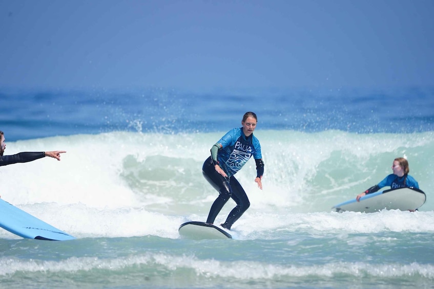 A person surfing on a wave with another person on a surfboard in the background. 3
