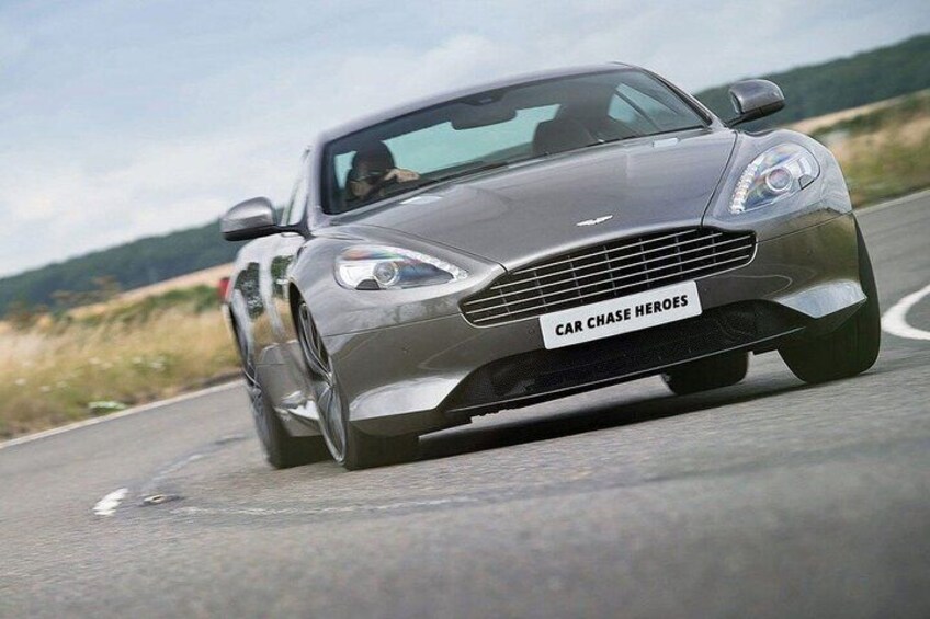 A silver sports car driving on a road with a license plate that reads 'CAR CHASE HEROES'. 5