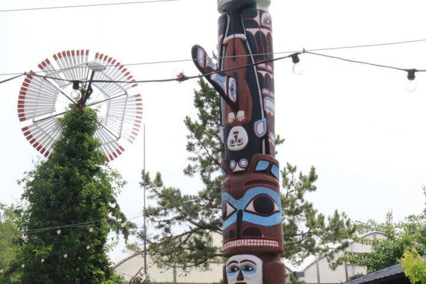 A totem pole with a windmill in the background. 4