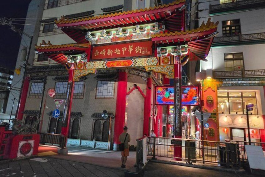 A traditional Chinese building with ornate red and gold decorations, a signboard, and a street sign. 1