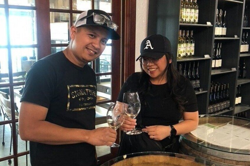 Two people holding wine glasses in a bar with shelves of bottles. 4