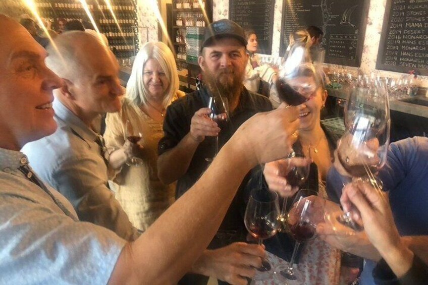 A group of people toasting with wine glasses at a bar. 1