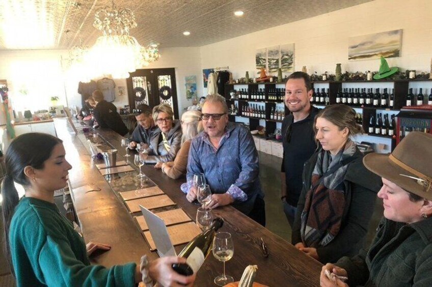 A group of people at a bar with wine glasses and bottles. 5