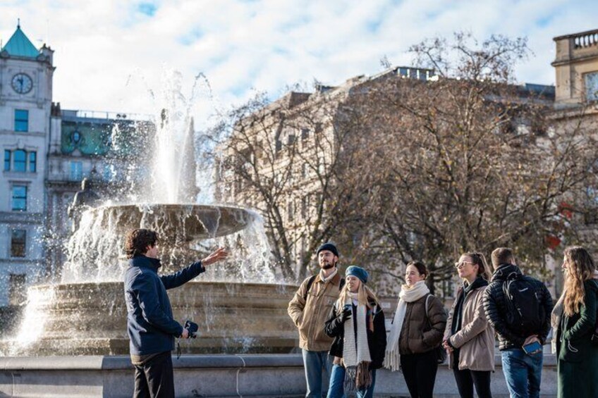 A group of people standing by a fountain with a historic building in the background. 4