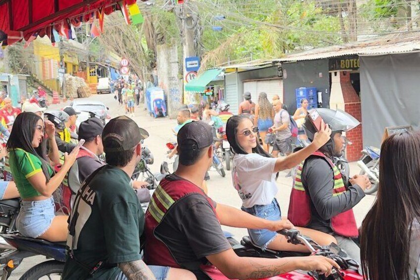 A street scene with people on motorcycles, a building with a sign, and a tree-lined street. 3