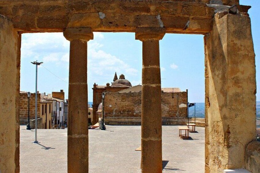 Ancient stone columns, a historic building, and a clear sky. 1