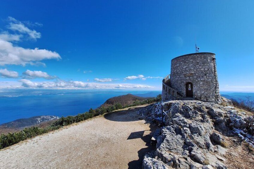 A stone tower on a hill with a clear sky. 1