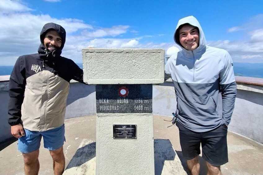 Two people standing next to a monument with inscriptions. 5