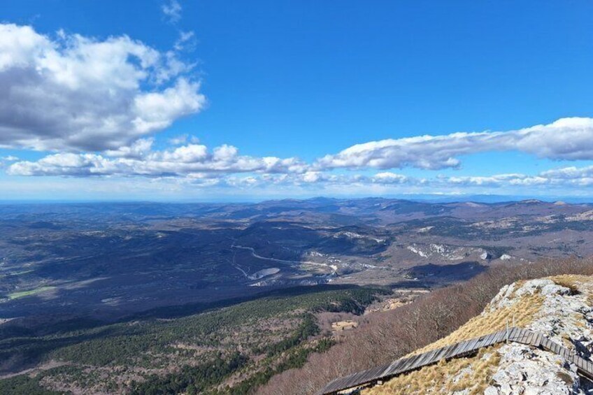 A mountainous landscape with a clear sky, a winding road, and a rocky outcrop. 2