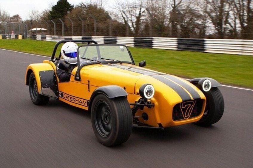 A yellow sports car with racing stripes on a racetrack. 1