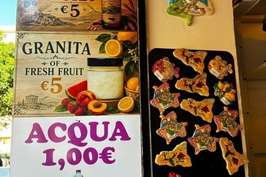A food stall with a sign offering granita of fresh fruit for €5 and acqua for €1.00. 2