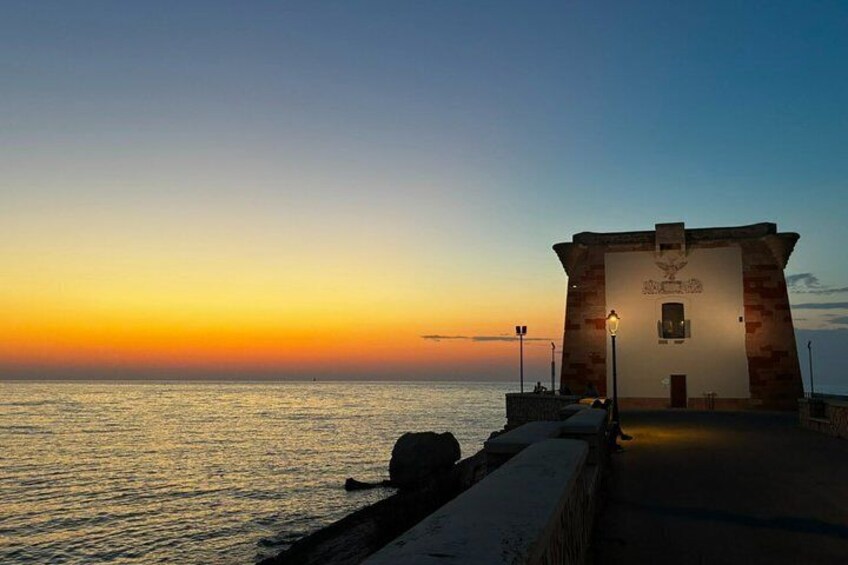 A coastal sunset with a building on a pier. 4