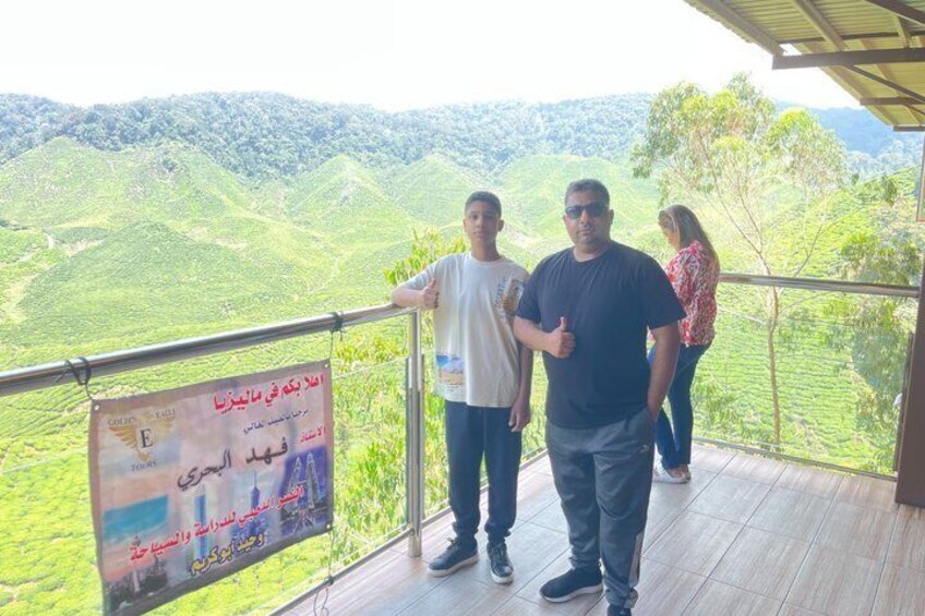 A group of people on a wooden deck overlooking a hilly landscape with lush greenery. 4