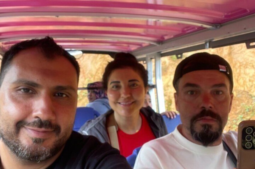 Three people seated inside a vehicle with a pink roof. 2