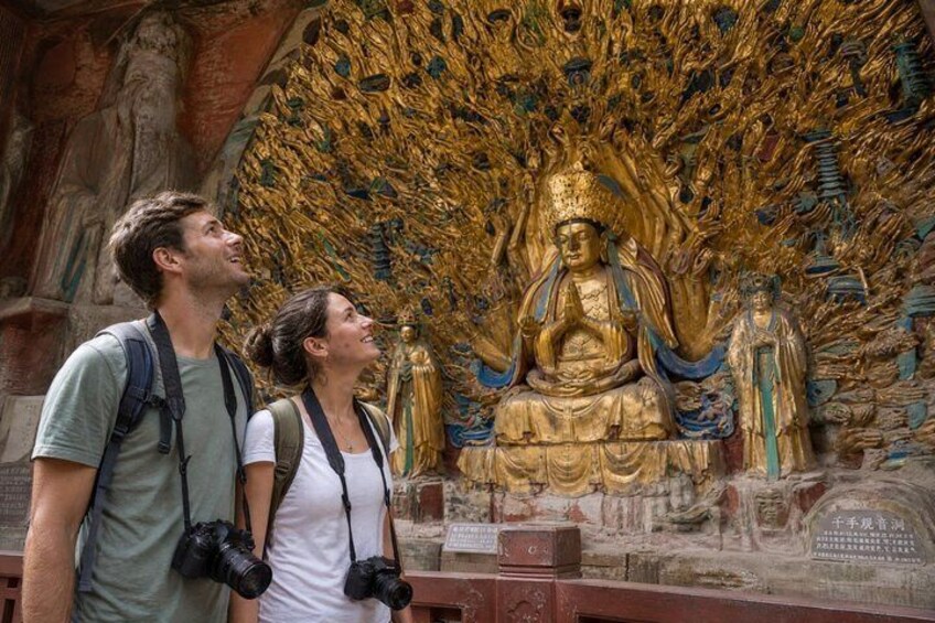 A large golden statue with intricate designs, surrounded by a detailed mural. 1