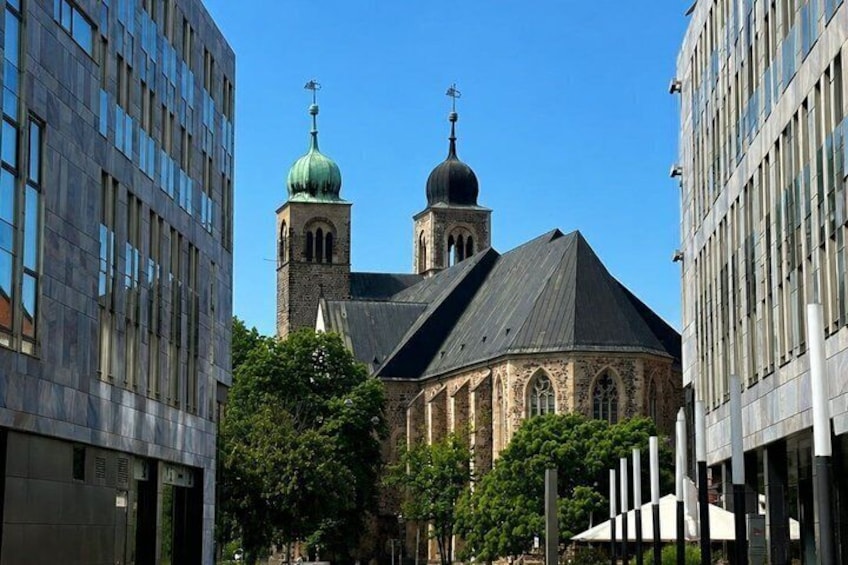 A church with a green dome and a bell tower, surrounded by modern buildings. 4