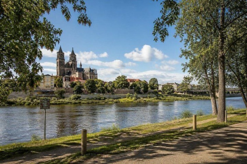 A river, a park with trees, and a historic building in the background. 5