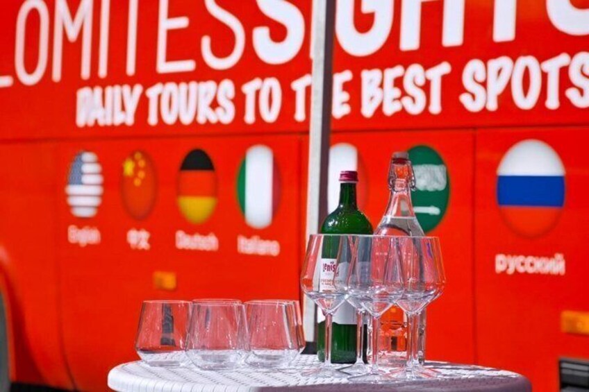 A table with empty glasses and bottles of alcohol, with flags of Germany, Italy, and Russia in the background. 3