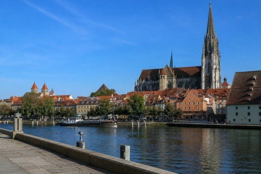 A river with a bridge, a cathedral, and red-roofed buildings. 2