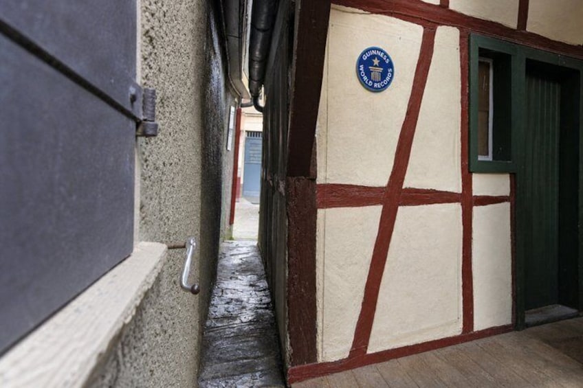 A narrow alleyway with a door on the left and a building with a Guinness logo on the right. 4