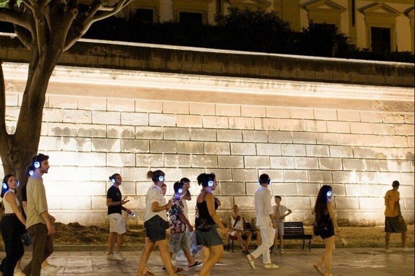 People walking along a sidewalk with a stone wall in the background. 5